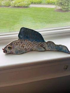 a fish figurine sitting on top of a window sill