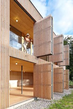 a person standing on the balcony of a wooden building with lots of wood slats