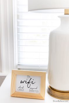 a white lamp sitting on top of a table next to a wooden frame with a sign