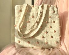 a white purse sitting on top of a pink bed next to a window with curtains