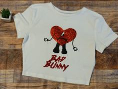 Bad Bunny Crop Top Fan Merch World's Hottest Tour 2022 Un Verano Sin Ti Shirt Glitter Red Heart and Font Choose between V-Neck or Crew Neck Crop Tops Crop Tops run small, make sure to size up Fitted Style Crop Top Style not loose style. Adult Sizes, Cotton/Polyester Blend. Black Font will be changed to white font if you order a black crop top to be more visible. CUSTOM ORDERS WELCOMED. We Carry Women Adult Sizes. All sizes, colors and options will be listed according to our inventory. SHIPPING F Bad Bunny Graduation Cap, Bad Bunny Shirt Ideas, Matching Bad Bunny Shirts, Bad Bunny Stuff, Merch Bad Bunny, Bad Bunny Toddler Shirt, Bad Bunny Shirts, Bad Bunny Tshirt, Ti Shirt