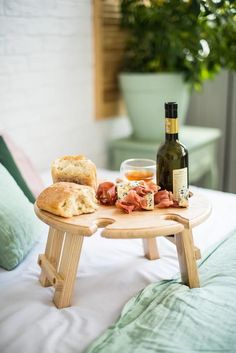 a table with bread, cheese and wine on it next to a bottle of wine