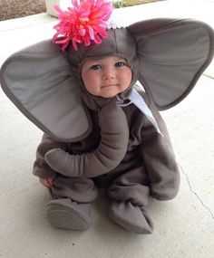 a baby wearing an elephant costume sitting on the ground