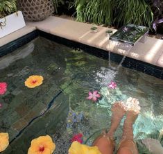 a person sitting in a pool with flowers on the ground and water running from it