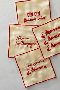 four embroidered handkerchiefs with words written on them, all in red and white colors