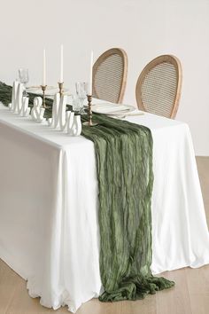 the table is set with two chairs and a white table cloth on it, along with candles