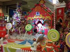 there are many candy land decorations in the store window and one girl is playing with lollipops