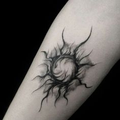 a black and white photo of a sun tattoo on the left arm, with an eyeball coming out of it