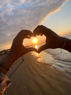 two hands making a heart shape with the sun setting in the background