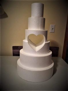 a three tiered white cake with a heart on top