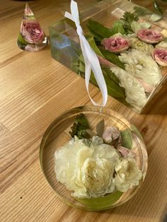 two clear bowls filled with flowers on top of a wooden table next to each other