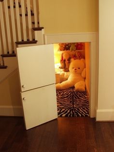 a white refrigerator freezer sitting inside of a kitchen next to a stair case filled with stuffed animals