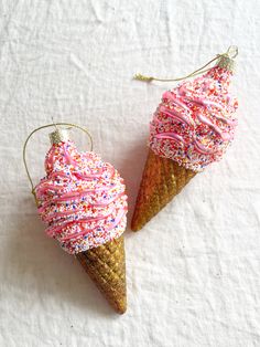 two ice cream cones decorated with sprinkles on top of a white surface