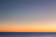 an airplane flying over the ocean at sunset