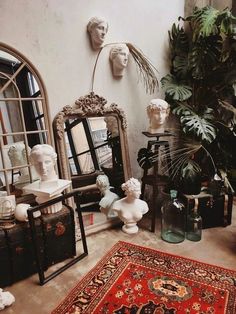 a room with mirrors, vases and statues on the floor