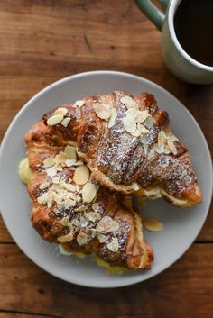 three pastries on a white plate next to a cup of coffee