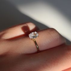 a close up of a person's hand holding a ring with a diamond on it