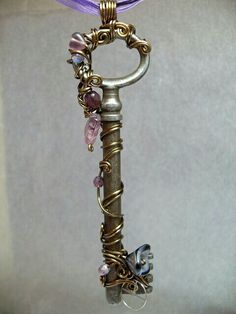 an old key is adorned with beads and other things to make it look like they are hanging from a chain