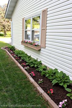 a flower bed in front of a house with flowers growing out of the window sill