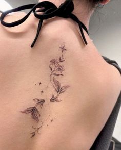 a woman's back tattoo with flowers and stars on her left side ribcage