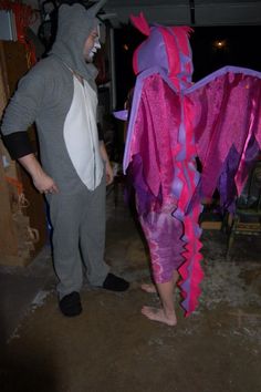 a man in a dragon costume standing next to a woman wearing a mask and tail