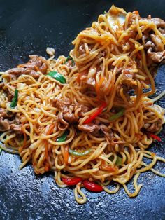 noodles with meat and vegetables on a black plate