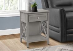 a grey end table with a plant on it in front of a gray leather chair