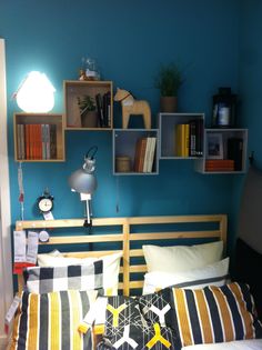 a bed room with a neatly made bed and bookshelves on the headboard