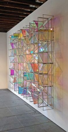 an art piece is displayed on the wall in front of a white wall with multiple colored squares