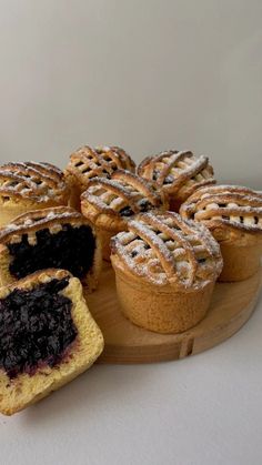 several pastries on a wooden platter with one cut in half and the other partially eaten