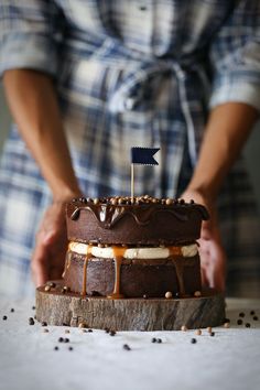 a person holding a cake with chocolate icing and an american flag on top