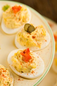 deviled eggs with olives and peppers on a plate, ready to be eaten