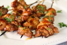 chicken skewers with sauce and parsley on a white plate