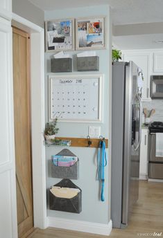 a kitchen with a refrigerator and calendars on the wall next to an open door