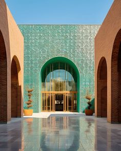 the entrance to a large building with arches and green doors on both sides, in front of a blue sky