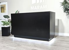 a black reception desk sitting in front of a plant