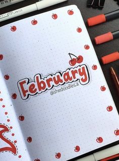 an open notebook with the word february written in red on it and some crayons next to it