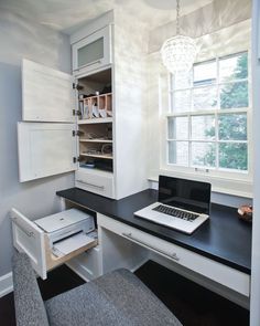 a laptop computer sitting on top of a desk next to a drawer and cabinet in a room