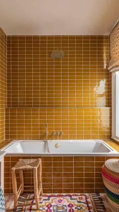 the bathroom is decorated in yellow and brown tiles, with an area rug on the floor