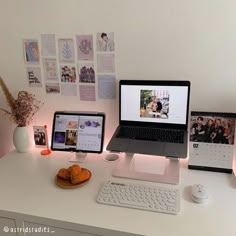 two laptops are sitting on a desk with pictures and other items around them,