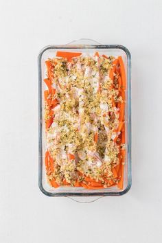 a casserole dish with carrots, meat and vegetables in it on a white surface