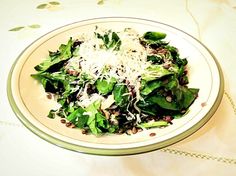 a white bowl filled with greens and shredded cheese