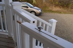 a car parked on the side of a road next to a white fence and gate