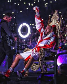 a man sitting on top of a chair in front of a crowd