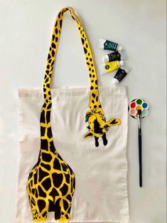 a giraffe painted on a canvas bag next to paintbrushes and markers