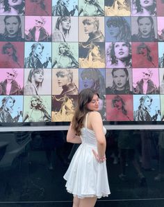 a woman standing in front of a wall with many pictures on it's side