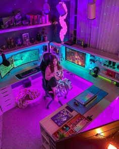 a woman sitting at a desk in front of two computer monitors with neon lights on them