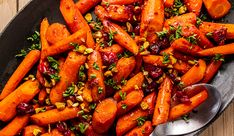 carrots with cranberry sauce and pistachio seeds in a black bowl