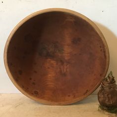 a wooden bowl sitting on top of a table next to a small potted plant