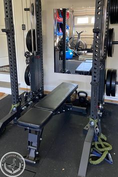 a home gym with weight benches and barbells on the floor in front of a mirror